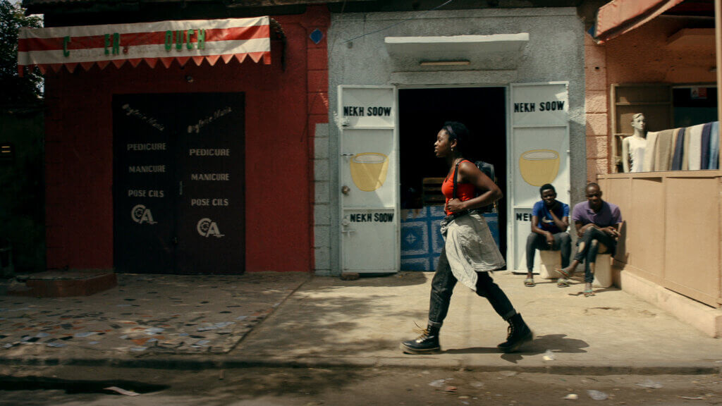 Nadège Bibo-Tansia marche dans une rue du Sénégal dans le film de Christophe Rolin Le Voyage de Talia